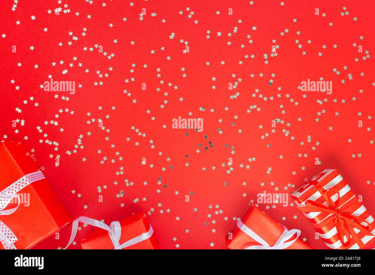 Arrière-plan de fête , coffrets cadeaux avec ruban et noeud sur un fond rouge avec des paillettes silver stars, télévision, vue d'en haut Banque D'Images