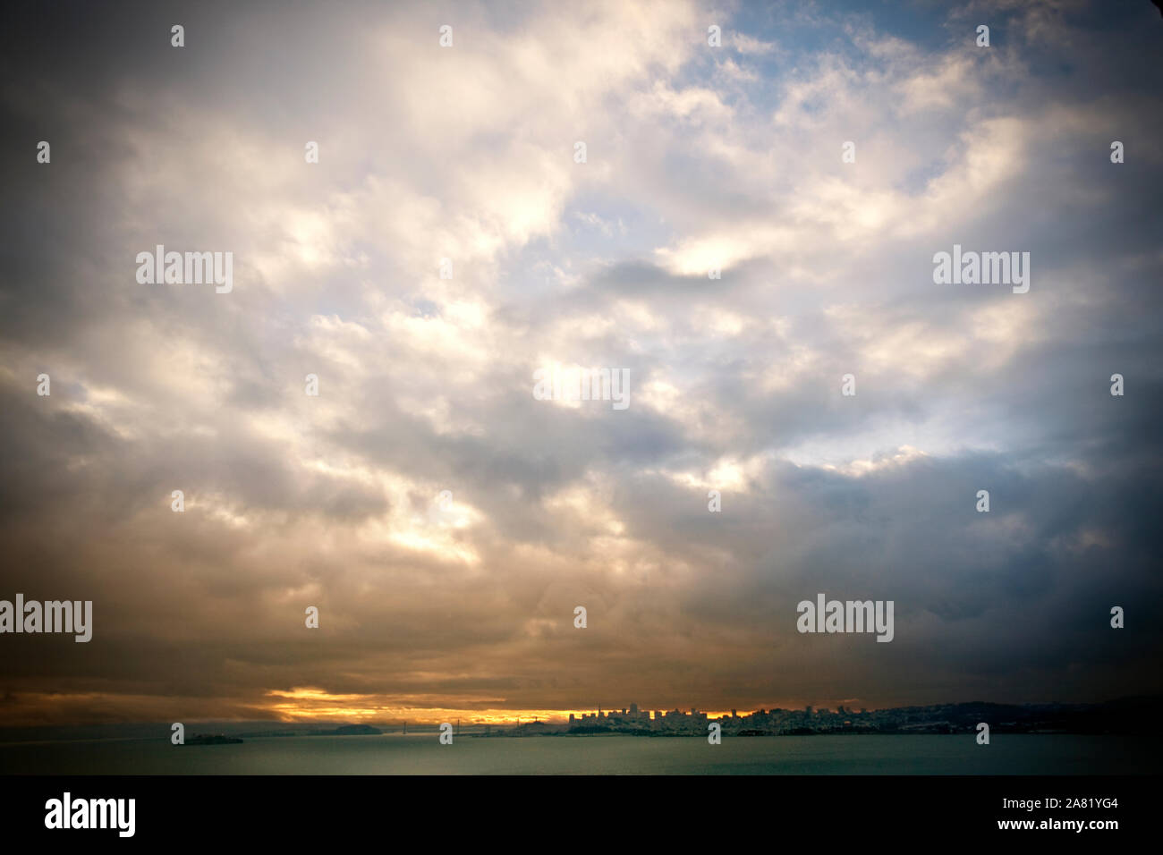 Coucher de soleil dans un ciel nuageux au-dessus d'une ville côtière. Banque D'Images
