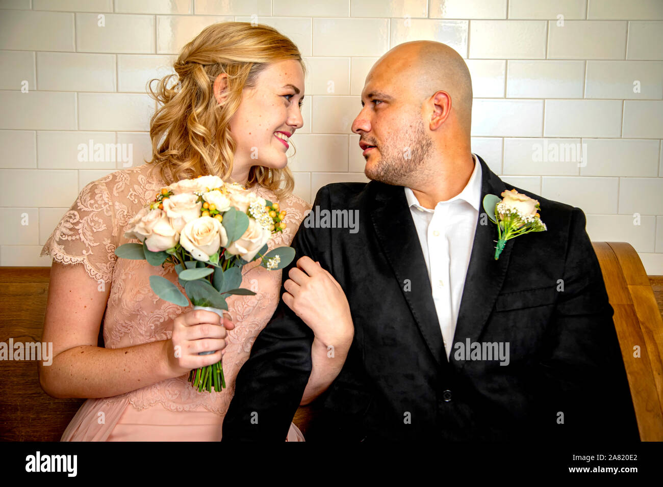 Close up of Bride and Groom en vêtements vintage assis et de toucher à l'un l'autre avec bride holding bouquet en attendant de se marier Banque D'Images