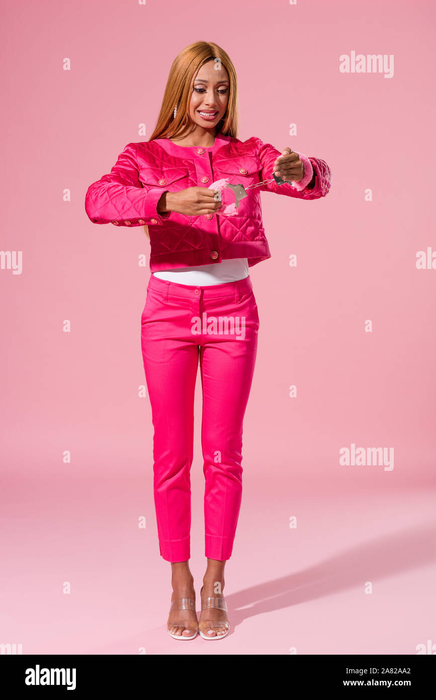 Choqué african american woman looking at menotté Main sur fond rose, concept Fashion poupée Banque D'Images