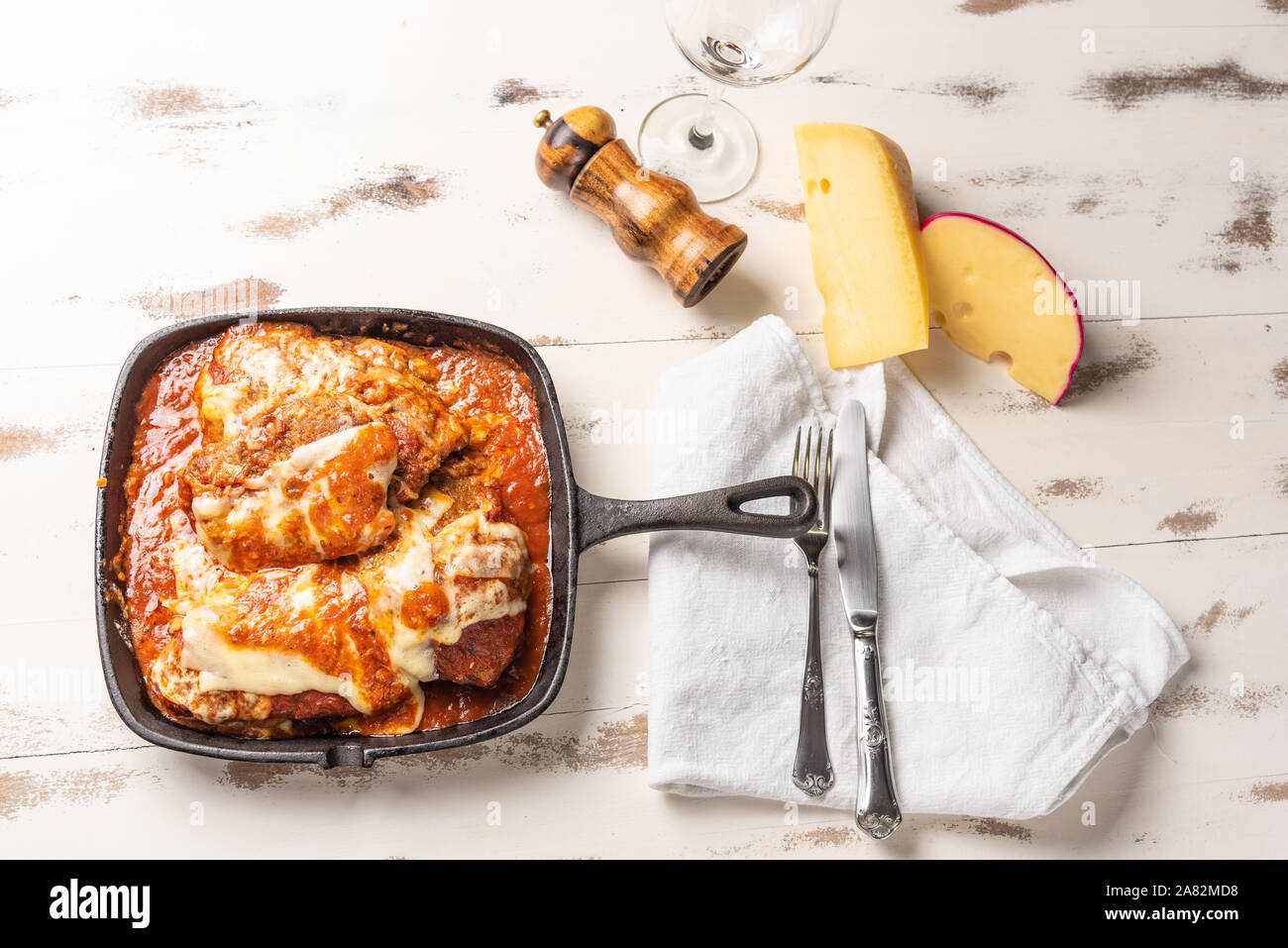 Parmegiana Steak aussi connu que Filet Parmegiana dans une poêle de fer  noir sur un fond blanc en bois, fromage et sauce tomate. Lumière douce, vue  du dessus. Télévision Photo Stock -