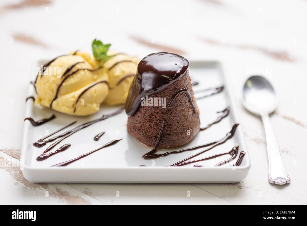Petit Gateau Dessert Petit Gateau Glace Vanille Et Sauce Au Chocolat Dans Une Assiette Blanche Sur Fond De Bois Blanc Photo Stock Alamy