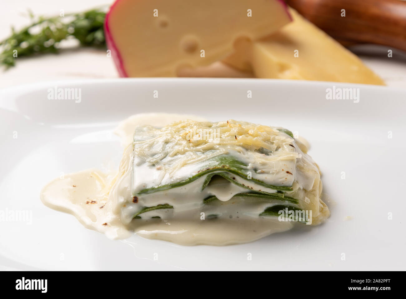 Des feuilles d'épinards frais lasagnes à la béchamel et de la sauce au fromage dans une assiette blanche. Lumière douce Banque D'Images
