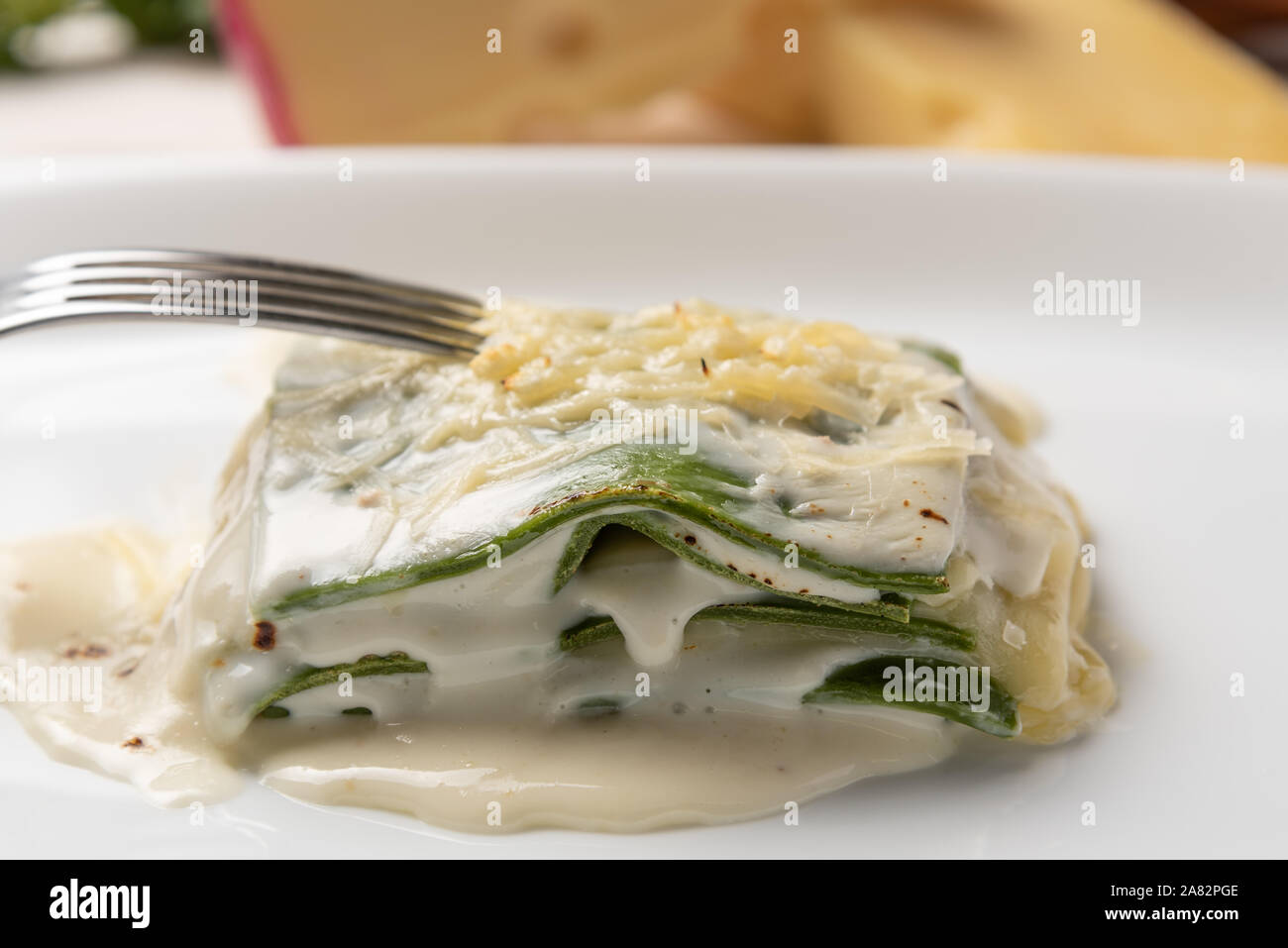 Des feuilles d'épinards frais lasagnes à la béchamel et de la sauce au fromage dans une assiette blanche. Lumière douce Banque D'Images