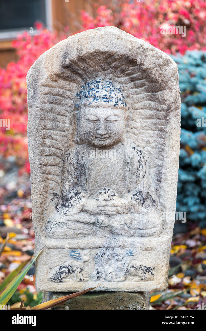 Statue du Bouddha sculptées en pierre dans le Lotus posent avec des couleurs d'automne dans l'arrière-plan Banque D'Images