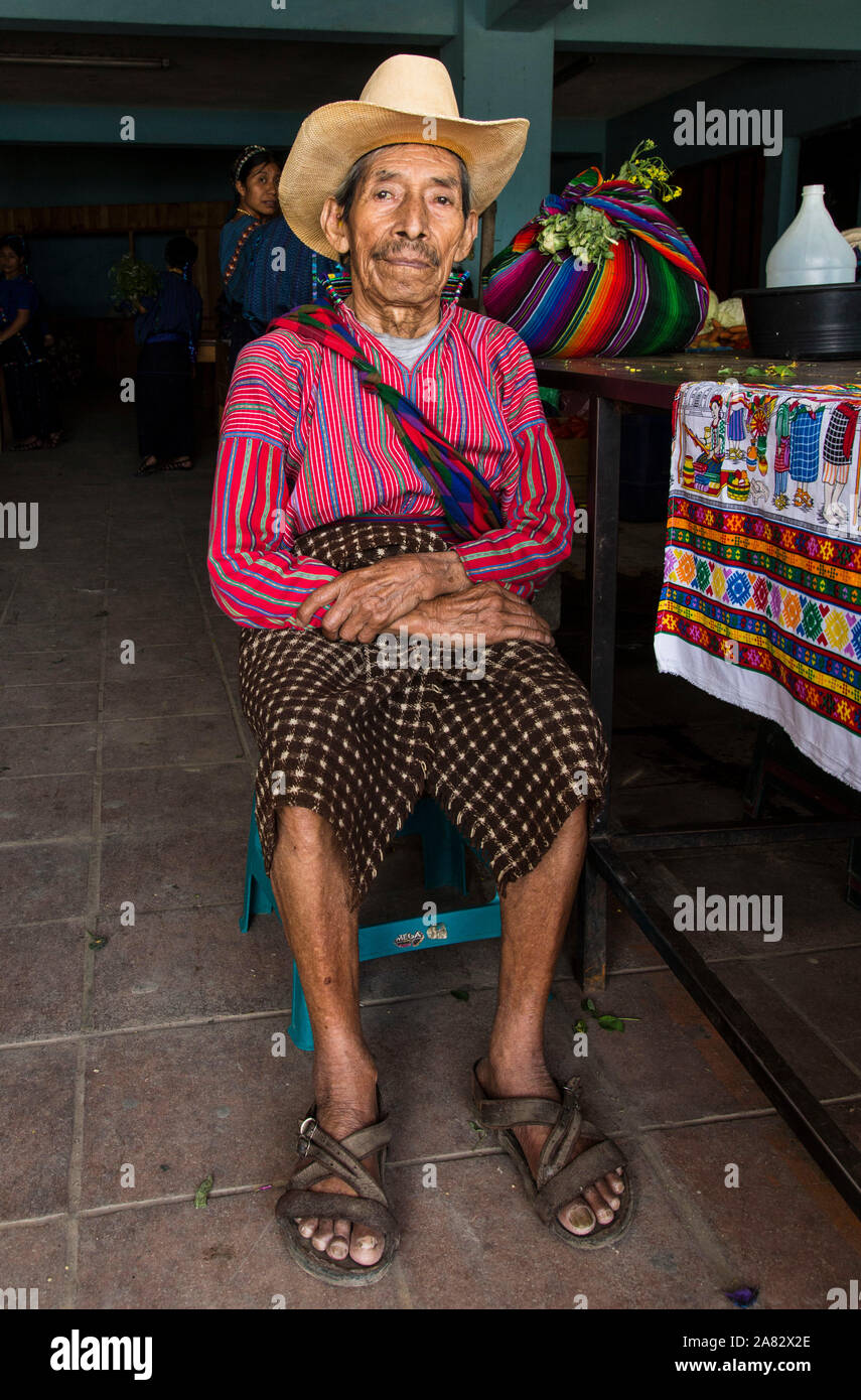 Un 80 ans agriculteur Maya se trouve dans le marché de San Antonio Palopo, Guatemala, porter la robe typique de la ville, y compris une chemise tissée à la main. Banque D'Images