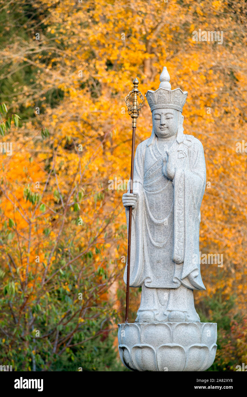 Un Bodhisattva Ksitigarbha, Bouddha, statue en pierre avec des couleurs d'automne jaune à l'arrière-plan Banque D'Images