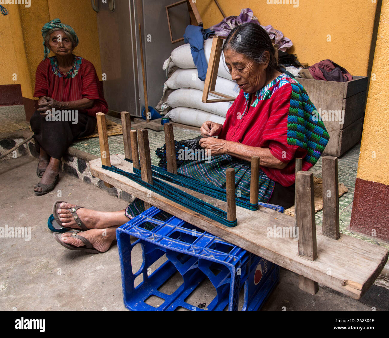 Une vieille femme maya en vêtements traditionnels vents thread en préparation pour le tissage sur un métier à l'arrière à Santa Cruz la Laguna, Guatemala. Banque D'Images