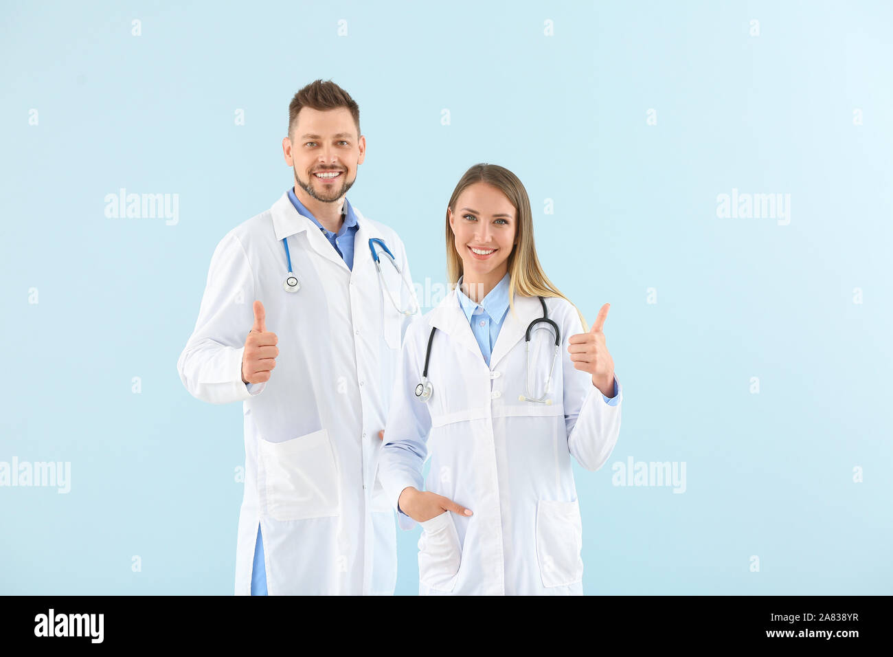 Les médecins hommes et femmes showing thumb-up sur fond de couleur de lumière Banque D'Images