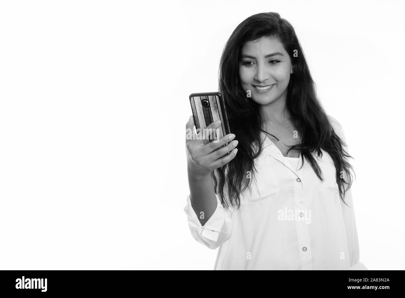 Studio shot of young woman smiling persan heureux lors de l'utilisation de téléphone mobile Banque D'Images