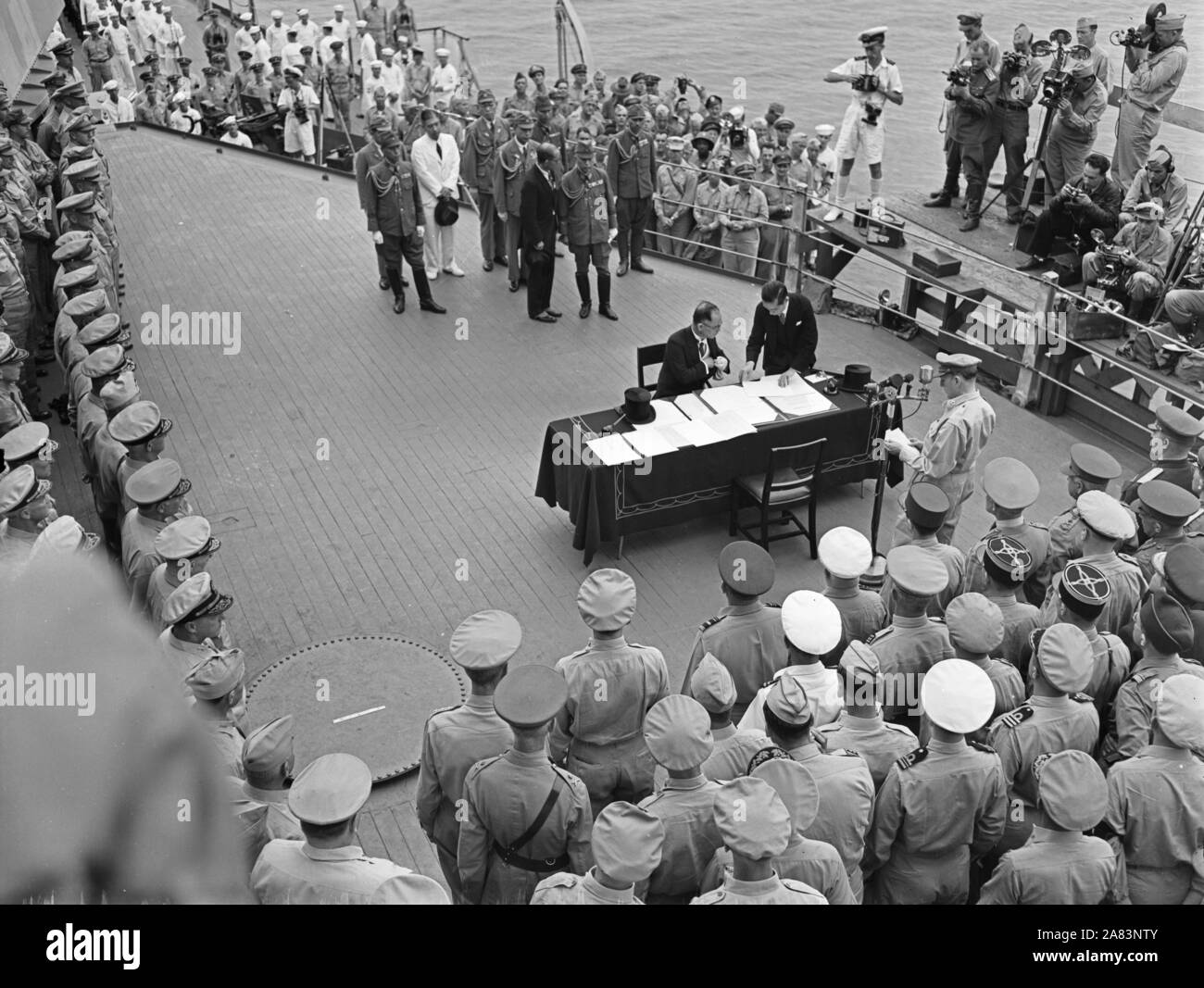 La Seconde Guerre mondiale photo - cérémonie de remise sur l'USS Missouri (BB-63) La baie de Tokyo. Le ministre japonais des affaires étrangères, Namoru Shigemitsu, signe les termes de la reddition comme officiers alliés regardez le 2 septembre 1945. Banque D'Images