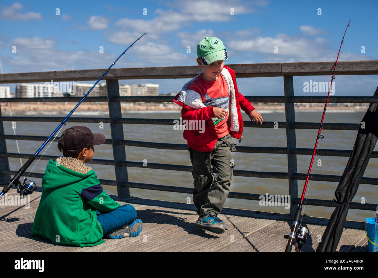 Deux garçons pêchant sur un quai près de la mer. Banque D'Images