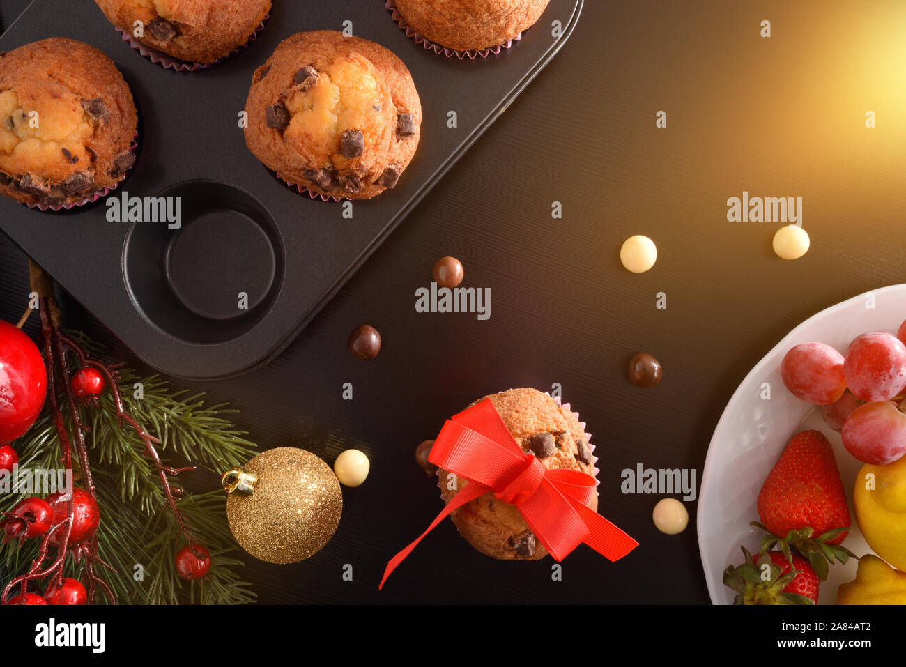 Muffins au chocolat faits maison fraîchement préparés sur la moisissure sur le tableau noir avec décoration de Noël et un plat de fruits. Composition horizontale. Vue d'en haut. Banque D'Images