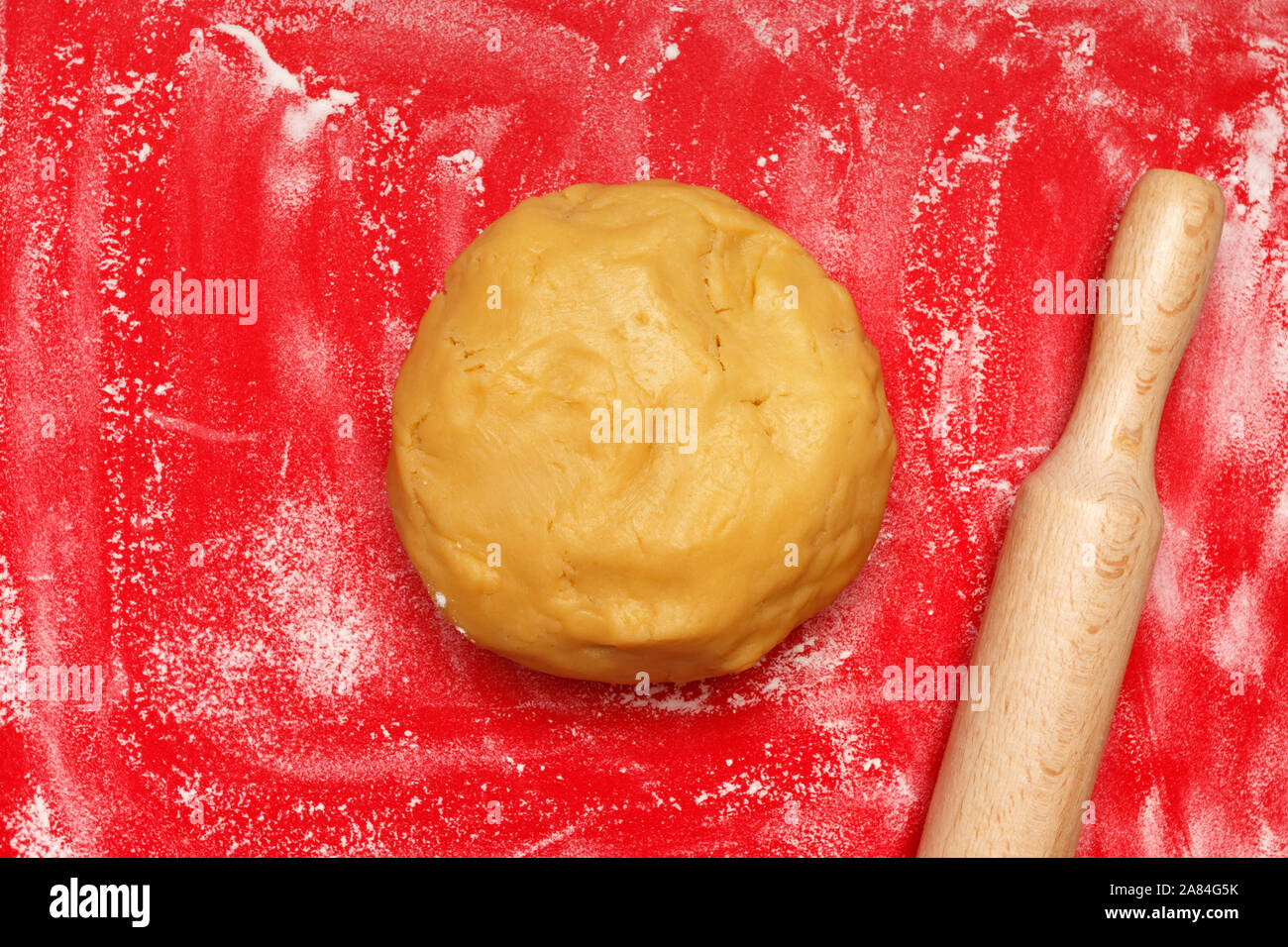 La cuisson de cookies de Noël à la maison. Pâte crue et de rouleau à pâtisserie sur une carte de couleur rouge. Banque D'Images