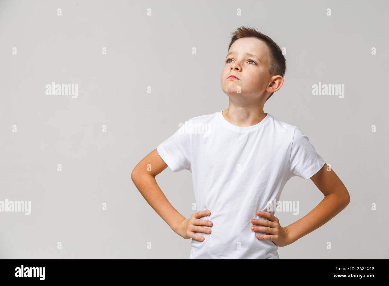 Portrait de jeune garçon avec les mains sur la taille de sa tête de levage sur fond blanc Banque D'Images