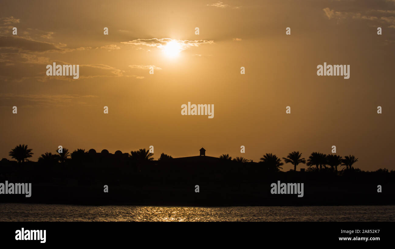 Palmiers et de bâtiments de l'hôtel en face de la magie le coucher du soleil en Egypte Banque D'Images