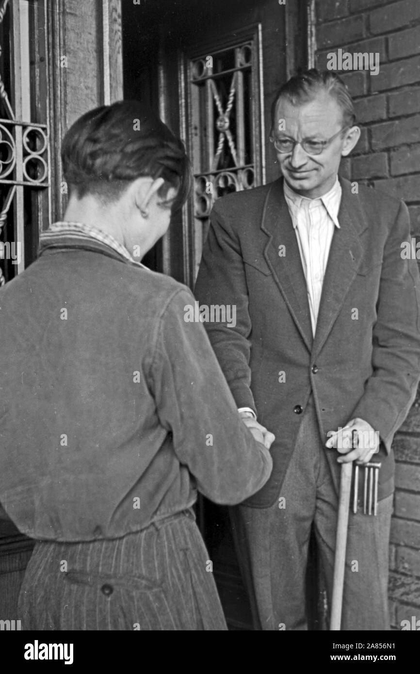 Ein Gefangener senneur Ausserhaus keht von Arbeit und wieder wird vom erwartet Pfarrer, Justizvollzugsanstalt Herford Deutschland 1950. Un prisonnier est de retour de son travail en prison et obtient l'accueilli par un membre du clergé, l'établissement correctionnel d'Herford Allemagne 1950. Banque D'Images