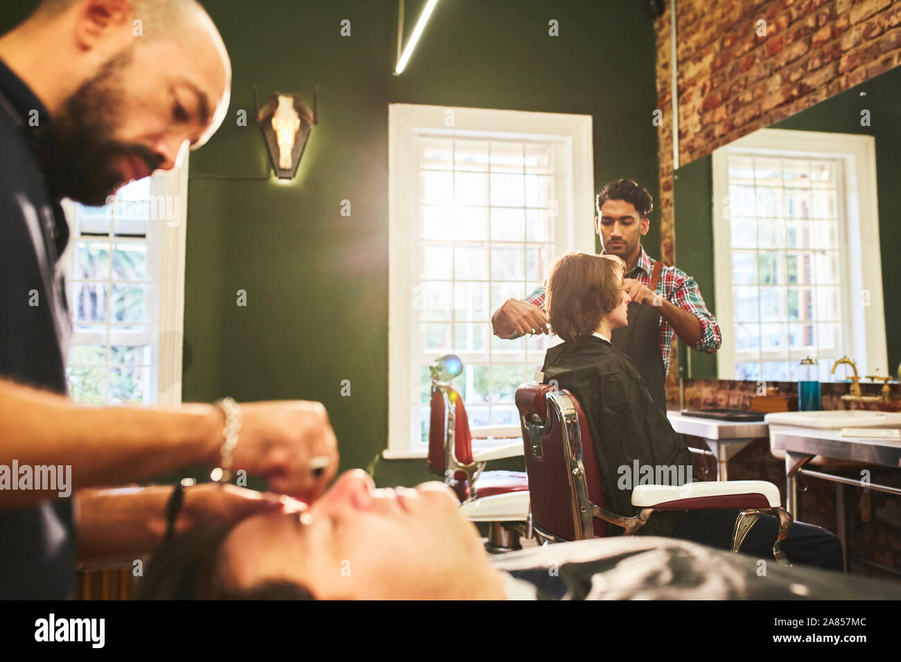 Les coiffeurs masculins travaillant dans un salon de barbier Banque D'Images