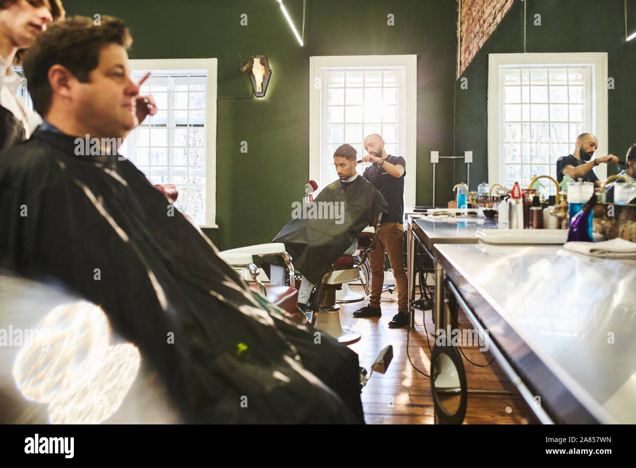 Les clients masculins et barbiers dans barbershop Banque D'Images