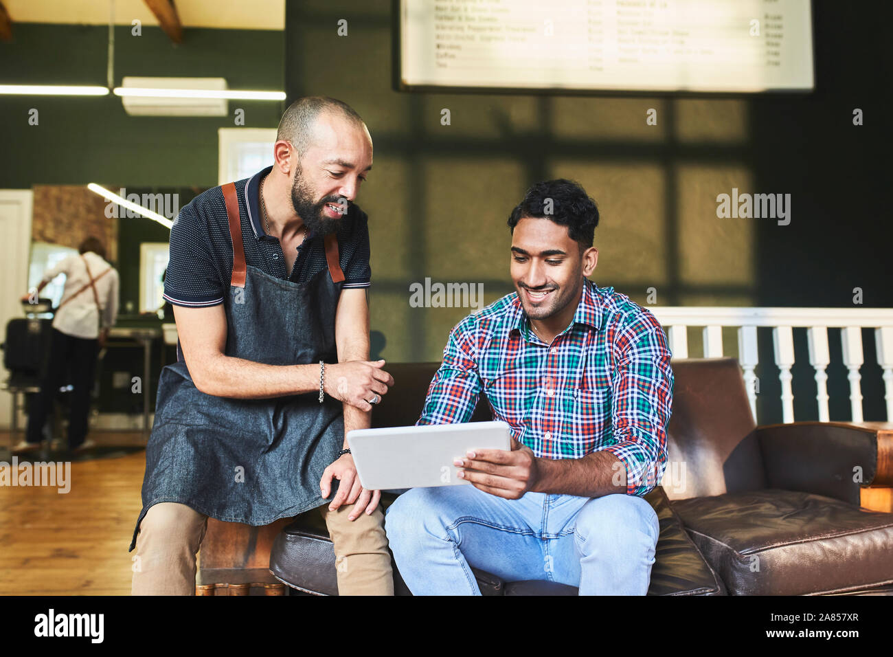 Salon de coiffure masculin et le client using digital tablet in barbershop Banque D'Images