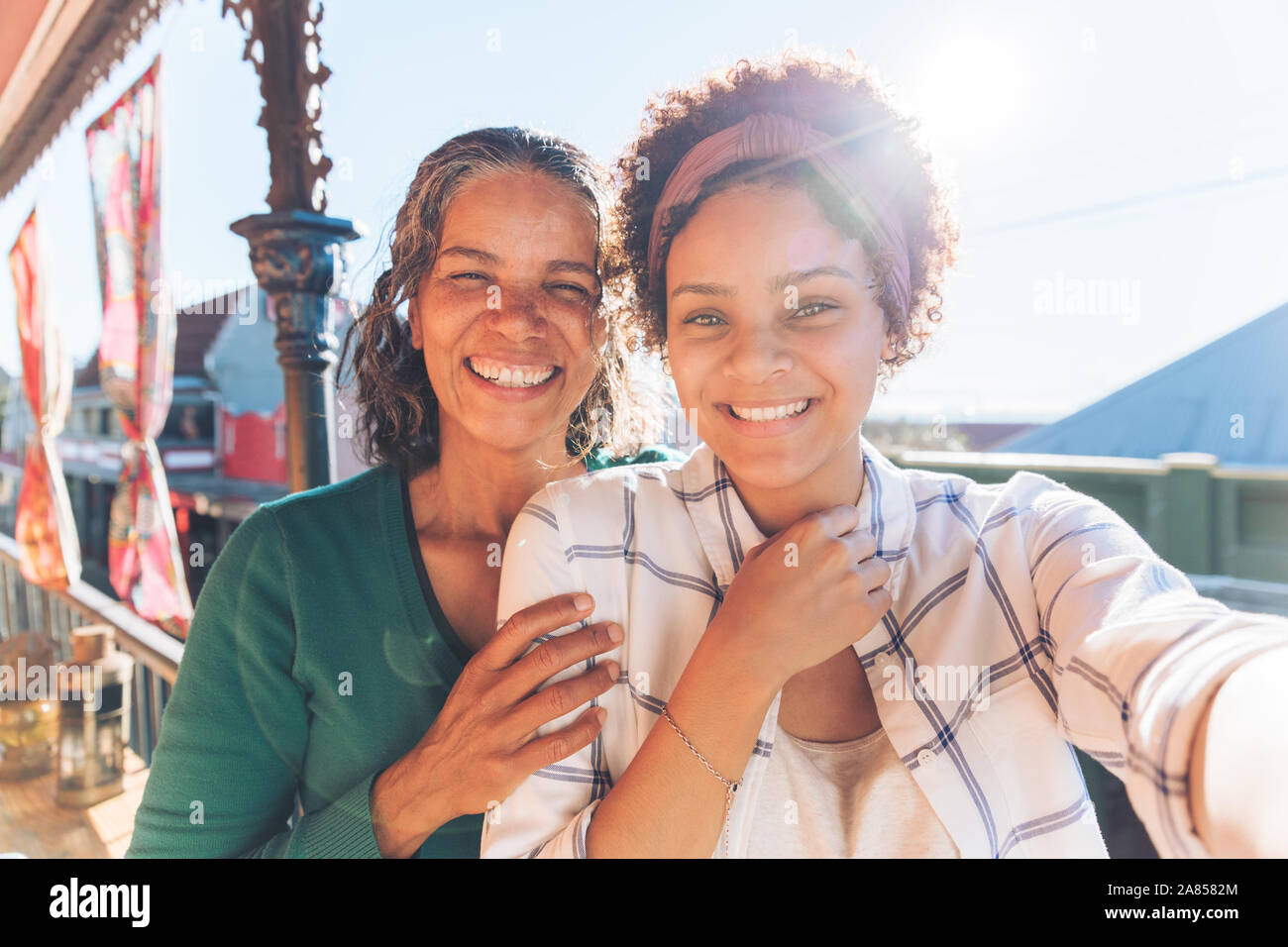 Point de vue portrait selfies souriant, heureux mère et fille sur balcon ensoleillé Banque D'Images