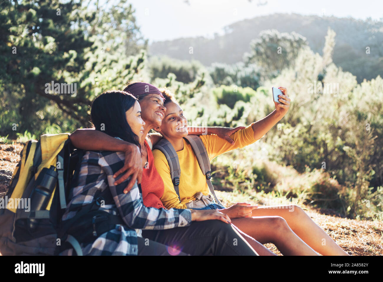 Heureuse mère et filles en tenant, les randonnées en selfies sunny woods Banque D'Images