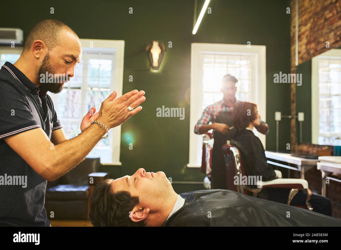 Coiffure homme debout à côté client dans un salon de barbier Banque D'Images