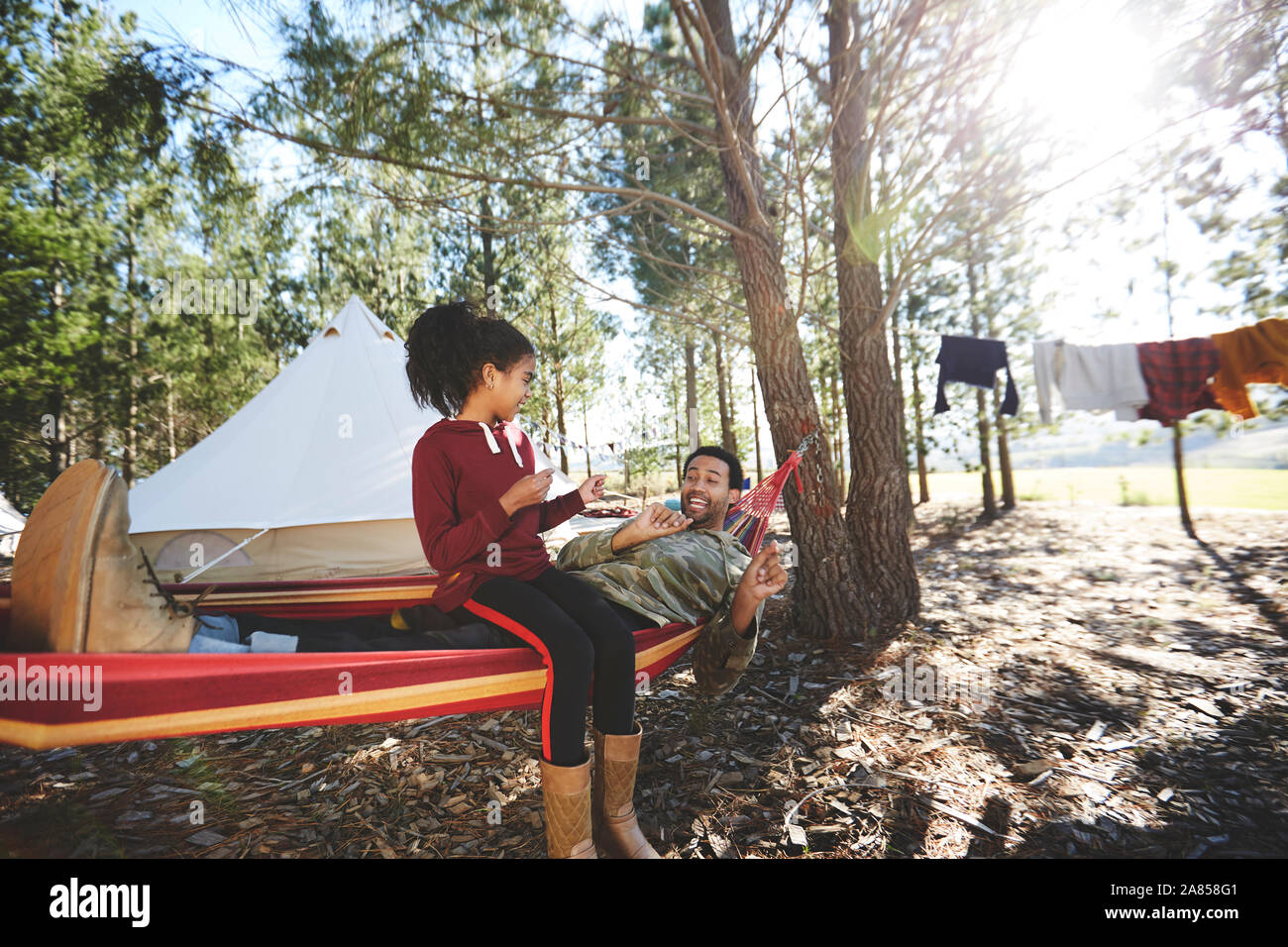 Père et fille en hamac de camping dans les bois Banque D'Images