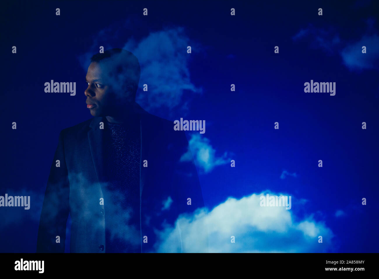 Double exposition businessman looking away against blue sky with clouds Banque D'Images