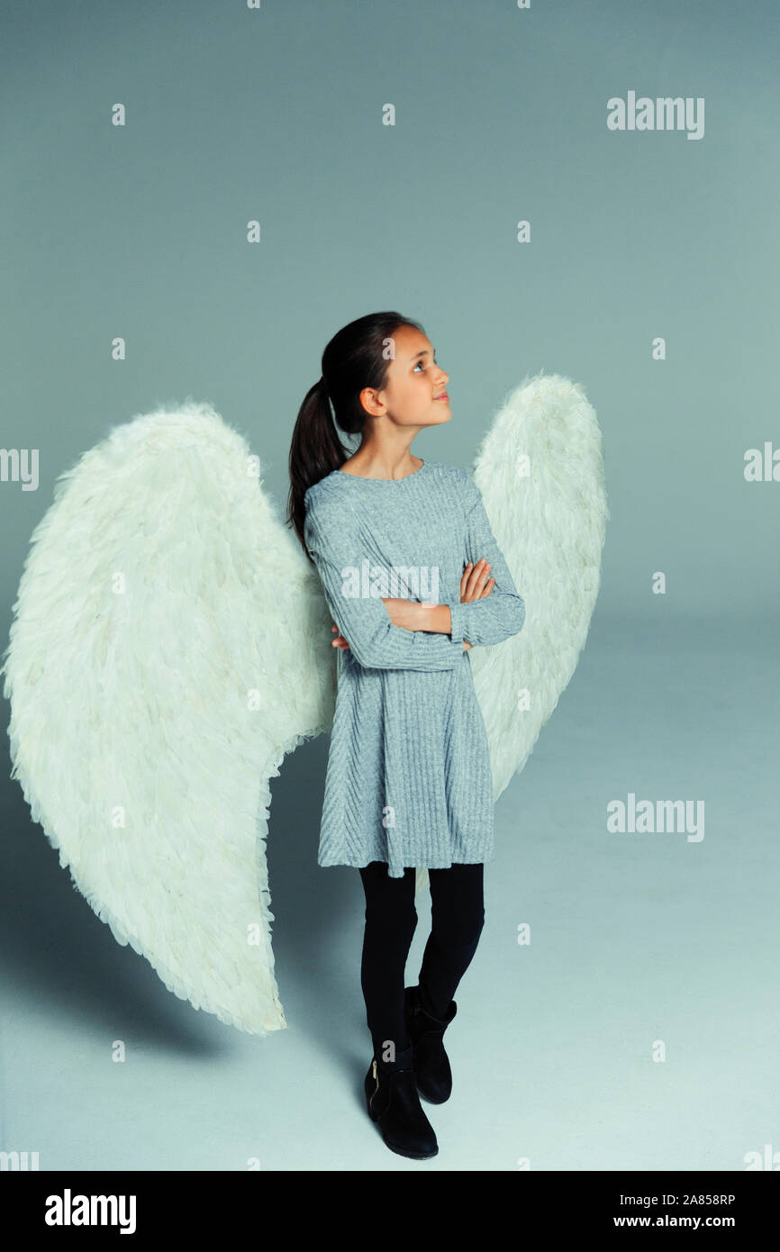 Portrait confiant, curieux girl wearing angel wings, looking up Banque D'Images