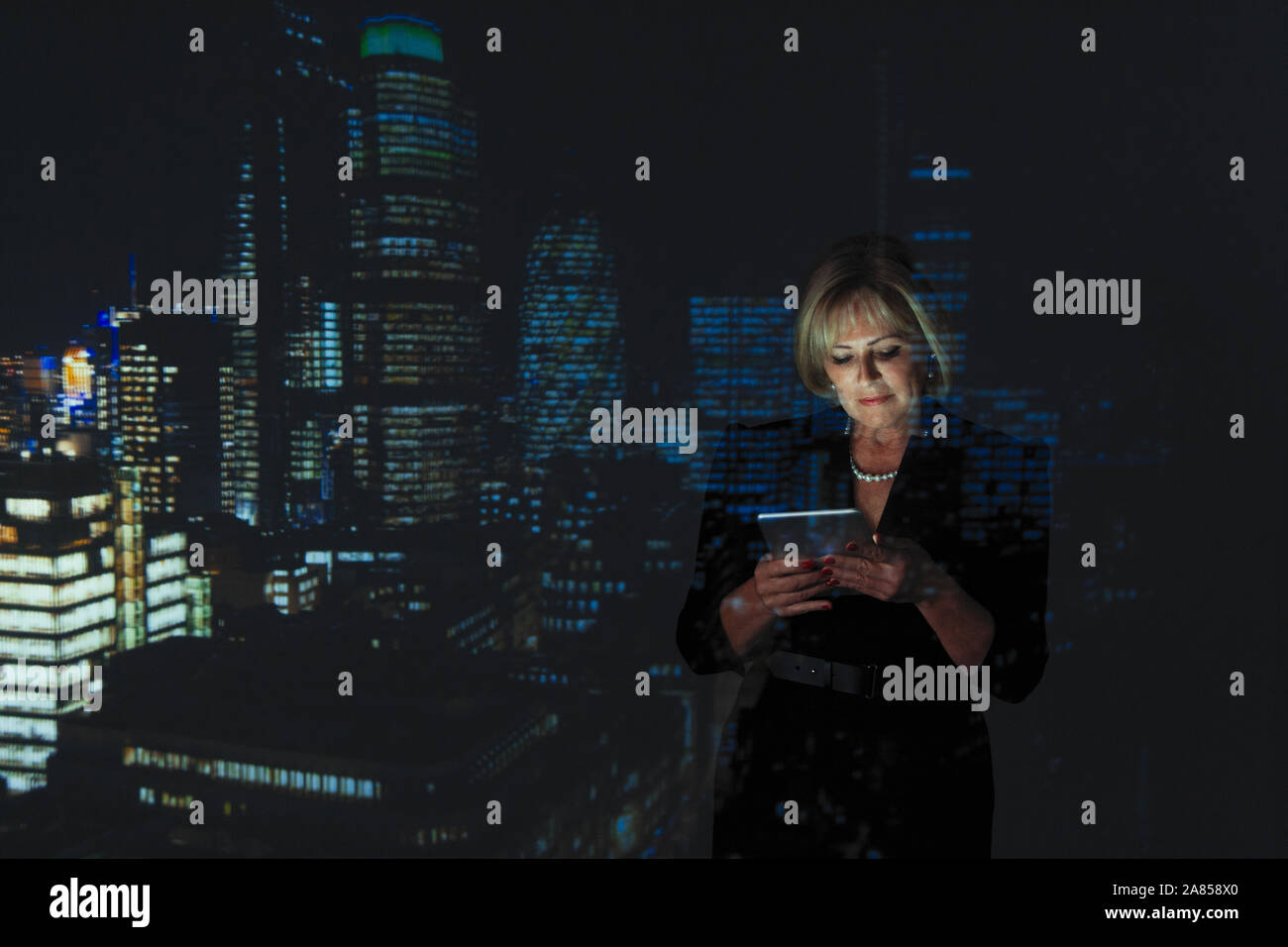 Double exposition businesswoman using digital tablet contre highrise des lumières dans la nuit Banque D'Images