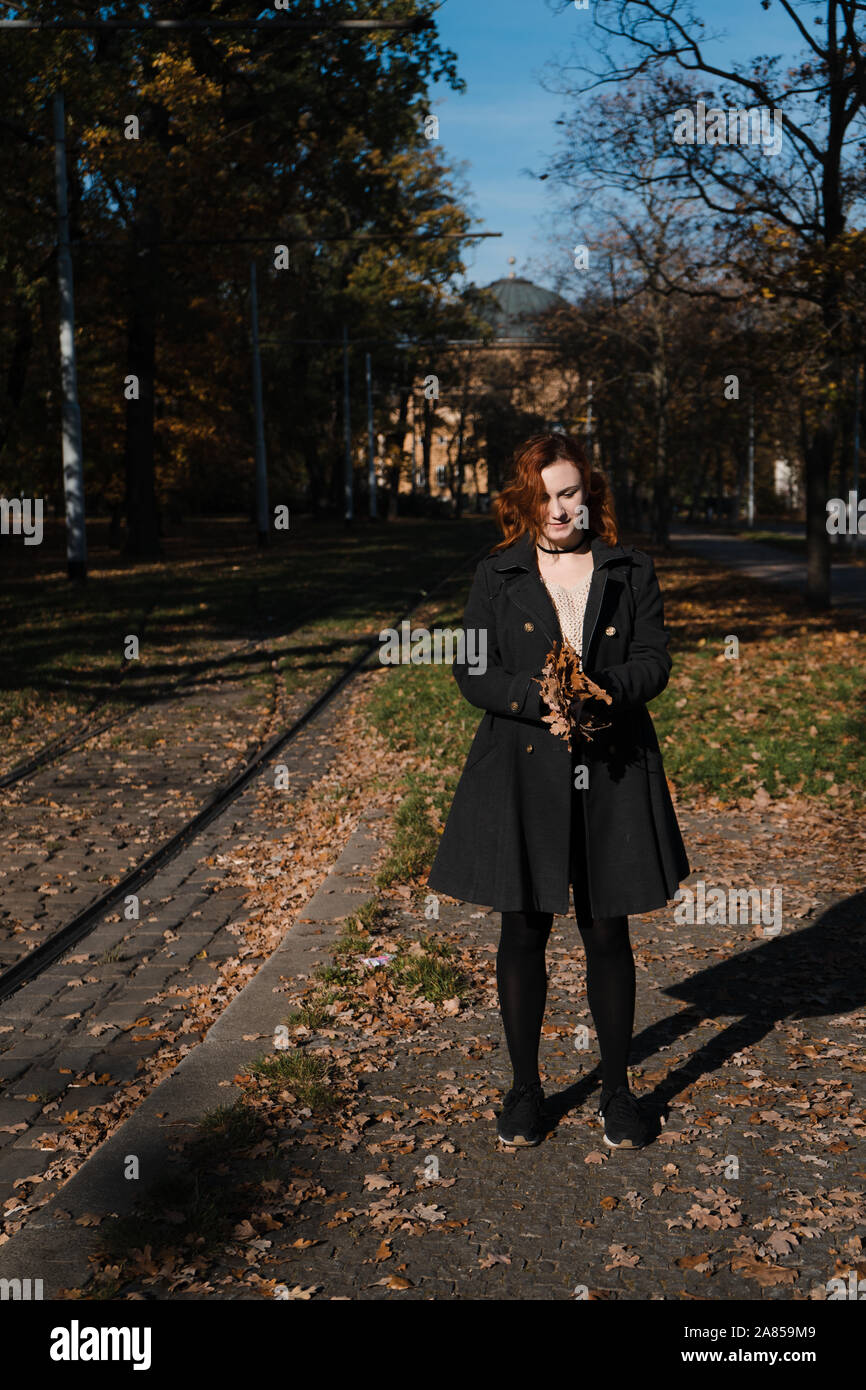 Heureux redhead woman throwing et jouer avec les feuilles d'automne à partir de la vie nouvelle à Prague Banque D'Images