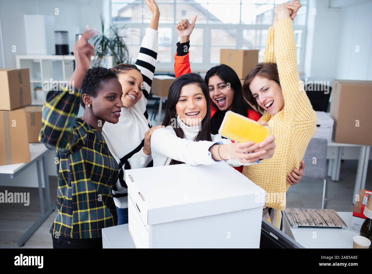 Les femmes d'affaires heureux déménagement dans de nouveaux bureaux, en tenant selfies Banque D'Images