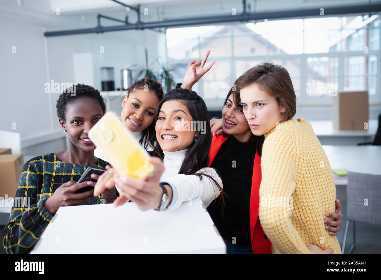 Les femmes d'affaires heureux déménagement dans de nouveaux bureaux, en tenant selfies Banque D'Images