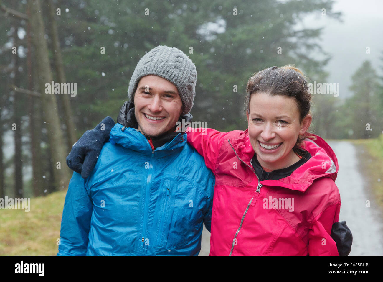 Portrait couple heureux randonnées à rainy woods Banque D'Images