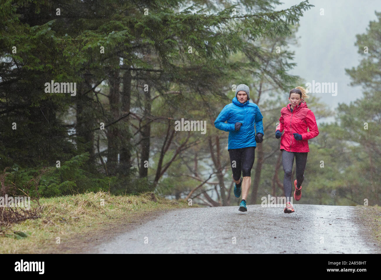 Couple jogging sur le sentier dans la région de Rainy woods Banque D'Images