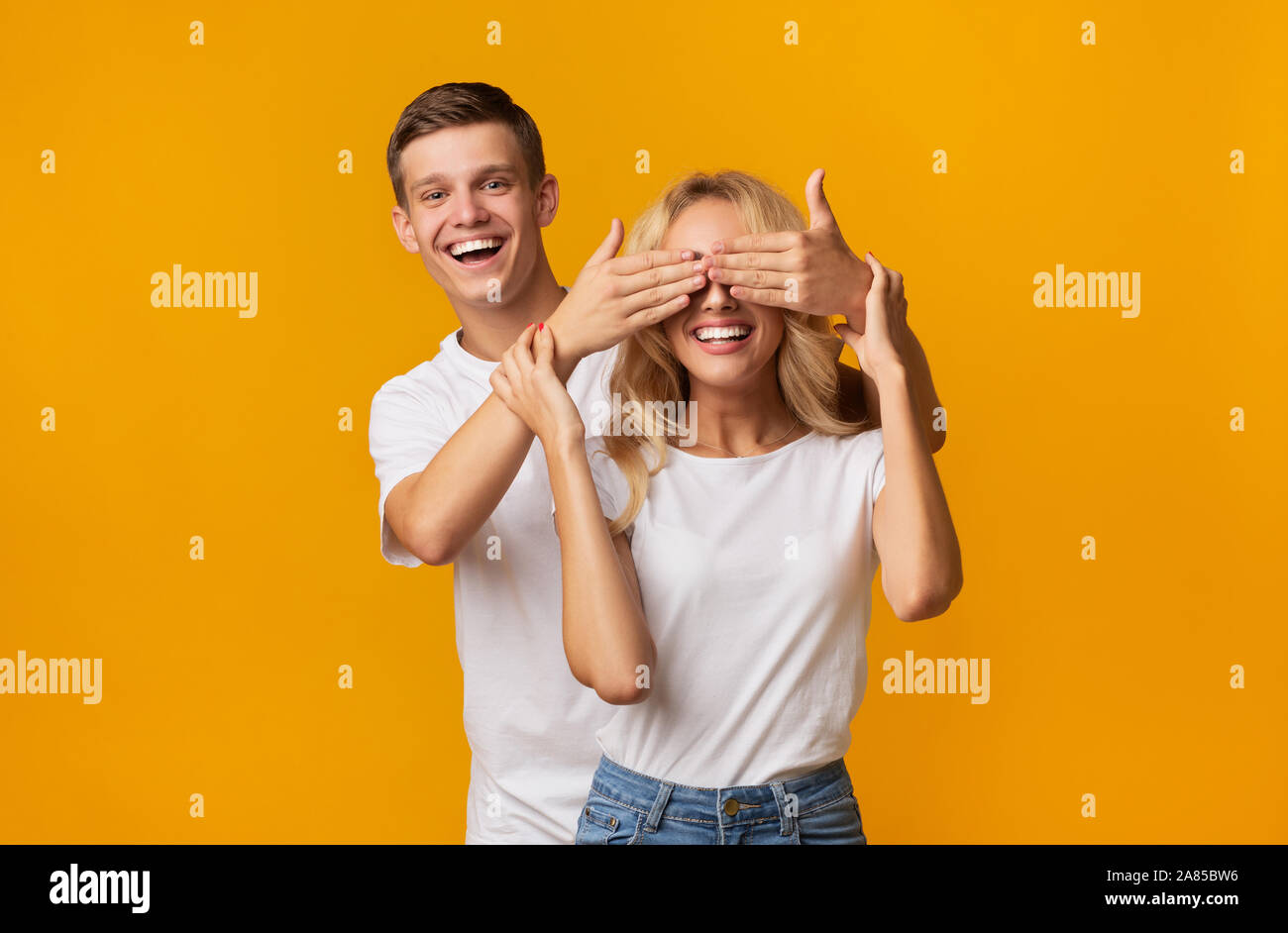 Jeune homme espiègle debout derrière copine et fermant les yeux Banque D'Images