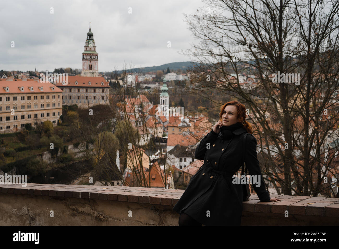 Redhead happy woman in Cesky Krumlov avec une vue sur les toits du centre-ville, château et Église de Saint Vitus Banque D'Images