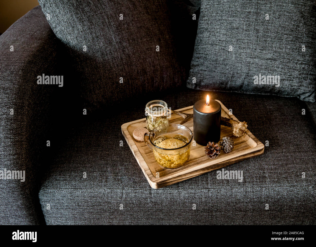 Vue rapprochée de style scandinave minimaliste couleur noir détails maison concept. Plateau en bois avec la cuisson à la vapeur de tisane, allumé la bougie noire, d Banque D'Images