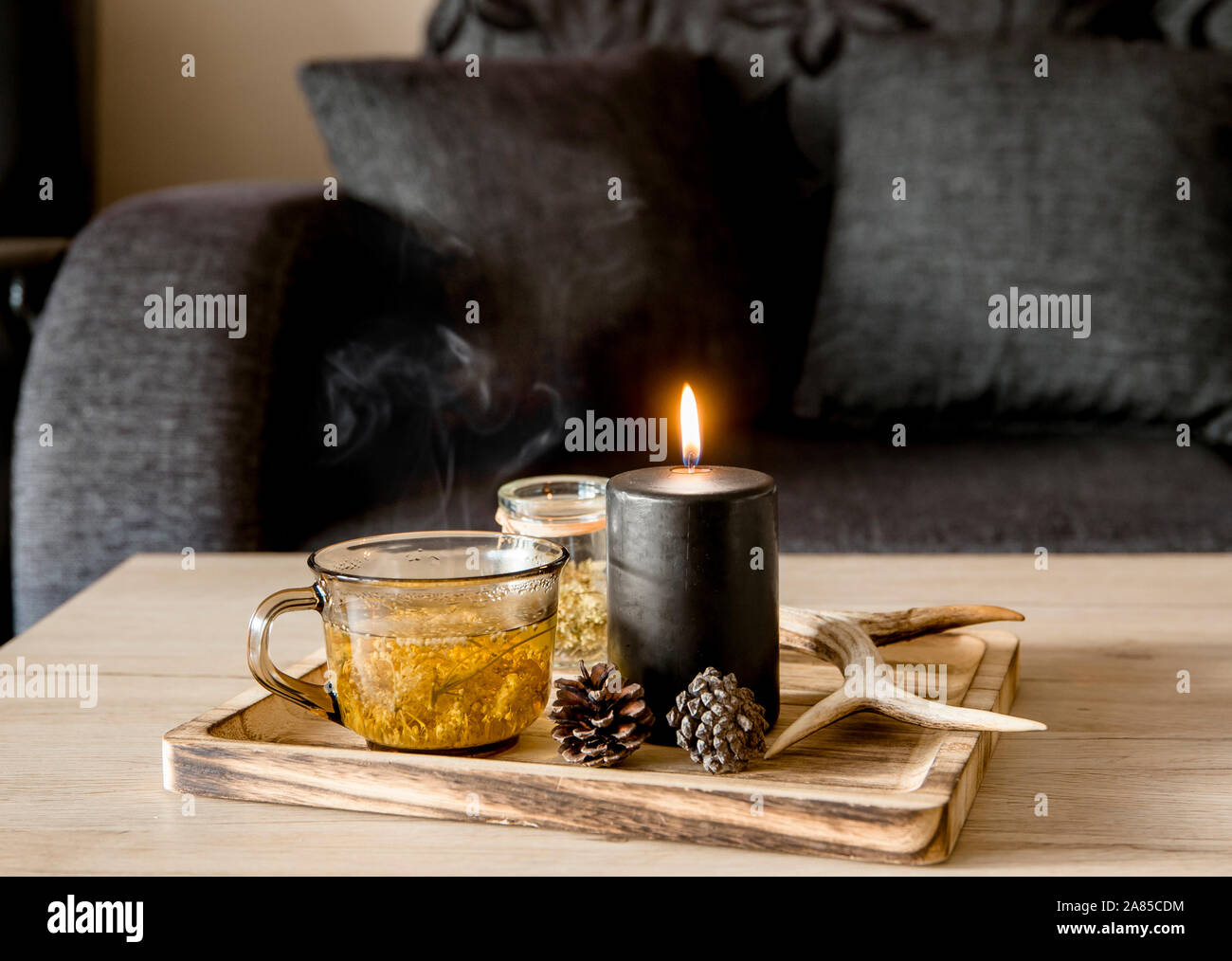 Vue rapprochée de style scandinave minimaliste couleur noir détails maison concept. Plateau en bois avec la cuisson à la vapeur de tisane, allumé la bougie noire, d Banque D'Images