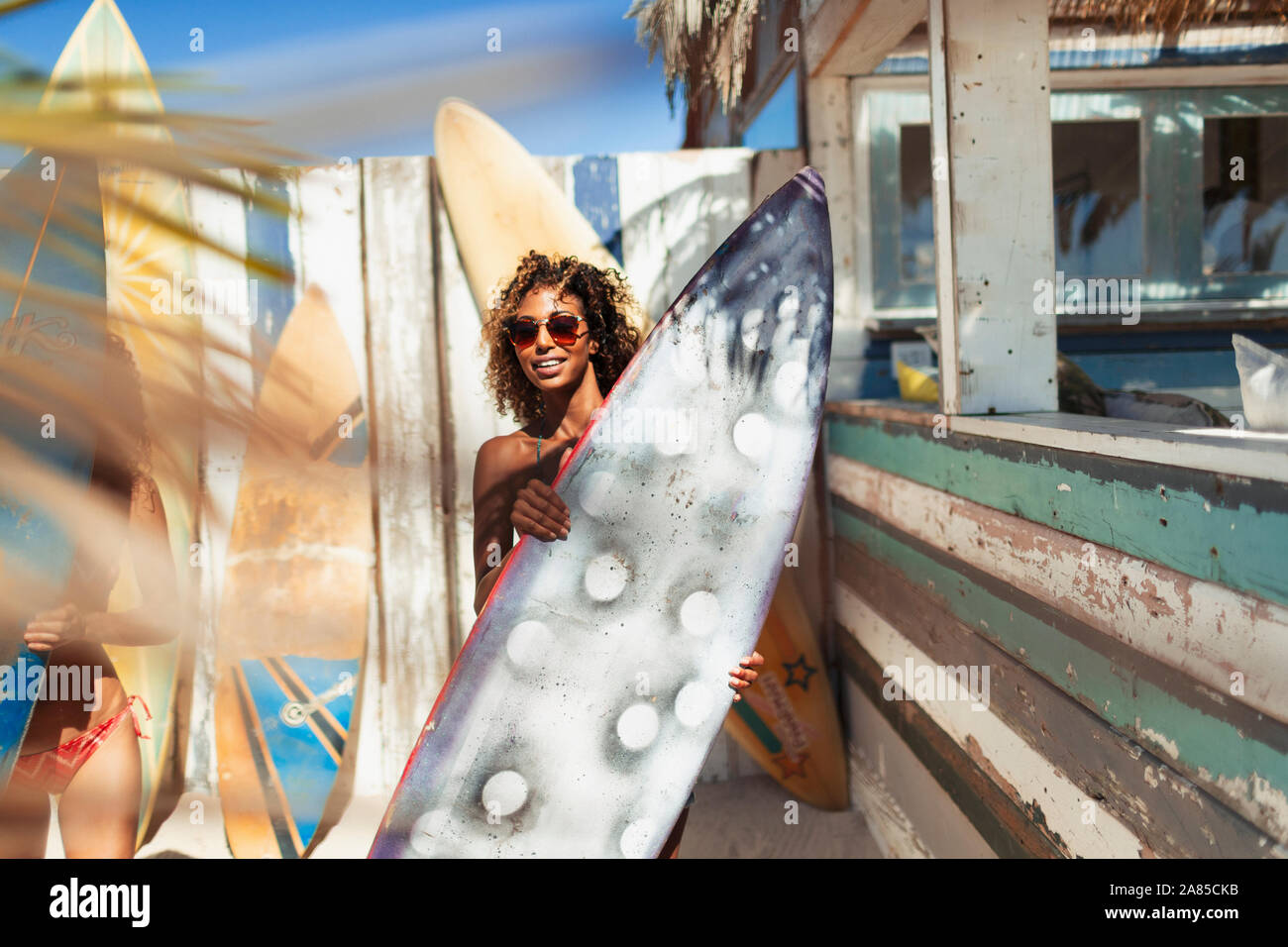 Portrait young woman with surfboard on sunny beach Banque D'Images