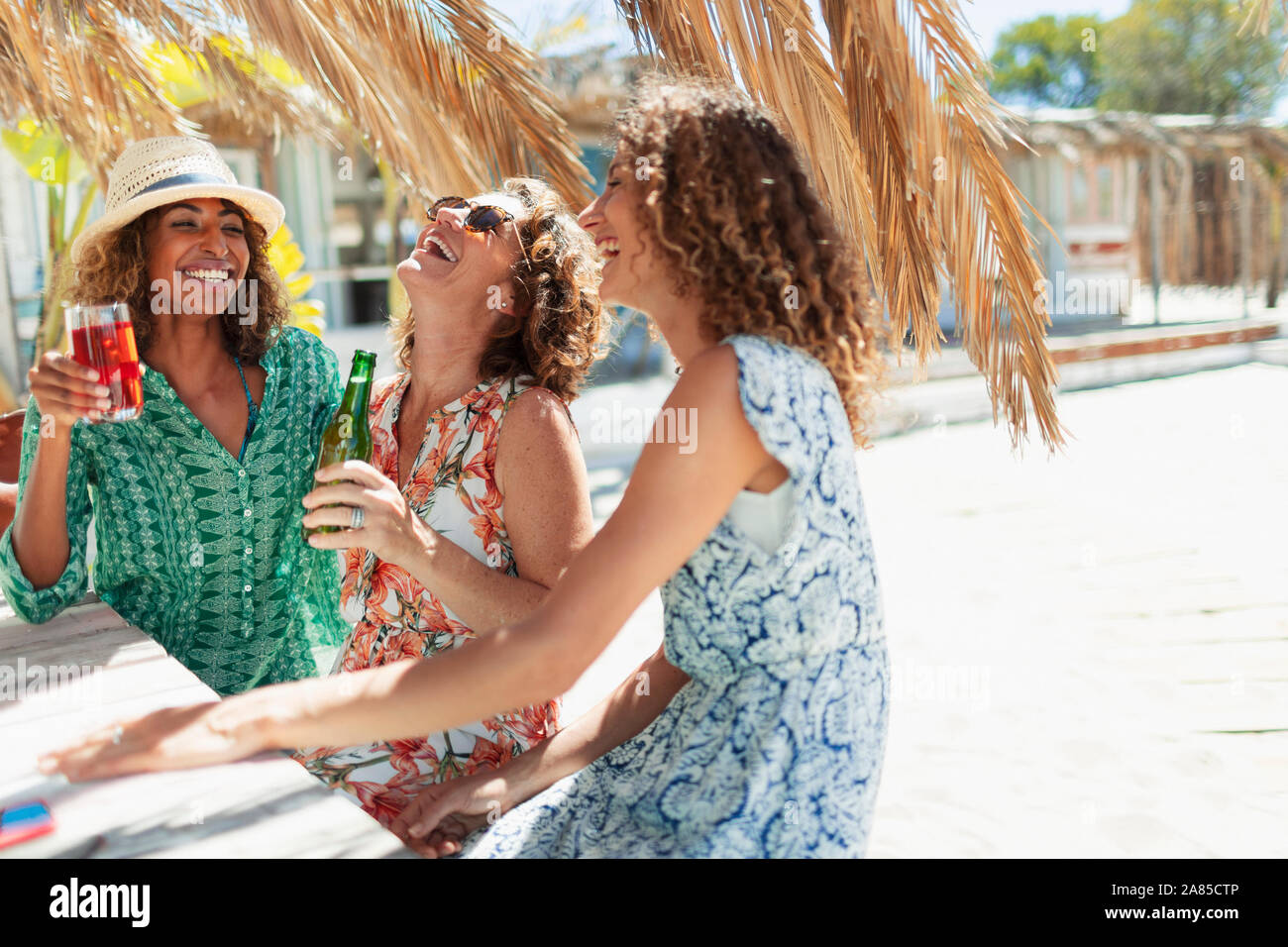 Happy women friends drinking à sunny beach bar Banque D'Images