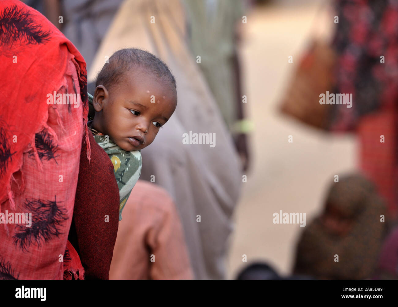 Un enfant somalien nouvellement arrivés dans le monde des sondages à partir de sa mère est de retour lors de l'attente dans le centre d'accueil du camp de réfugiés de Dagahaley au Kenya. Banque D'Images