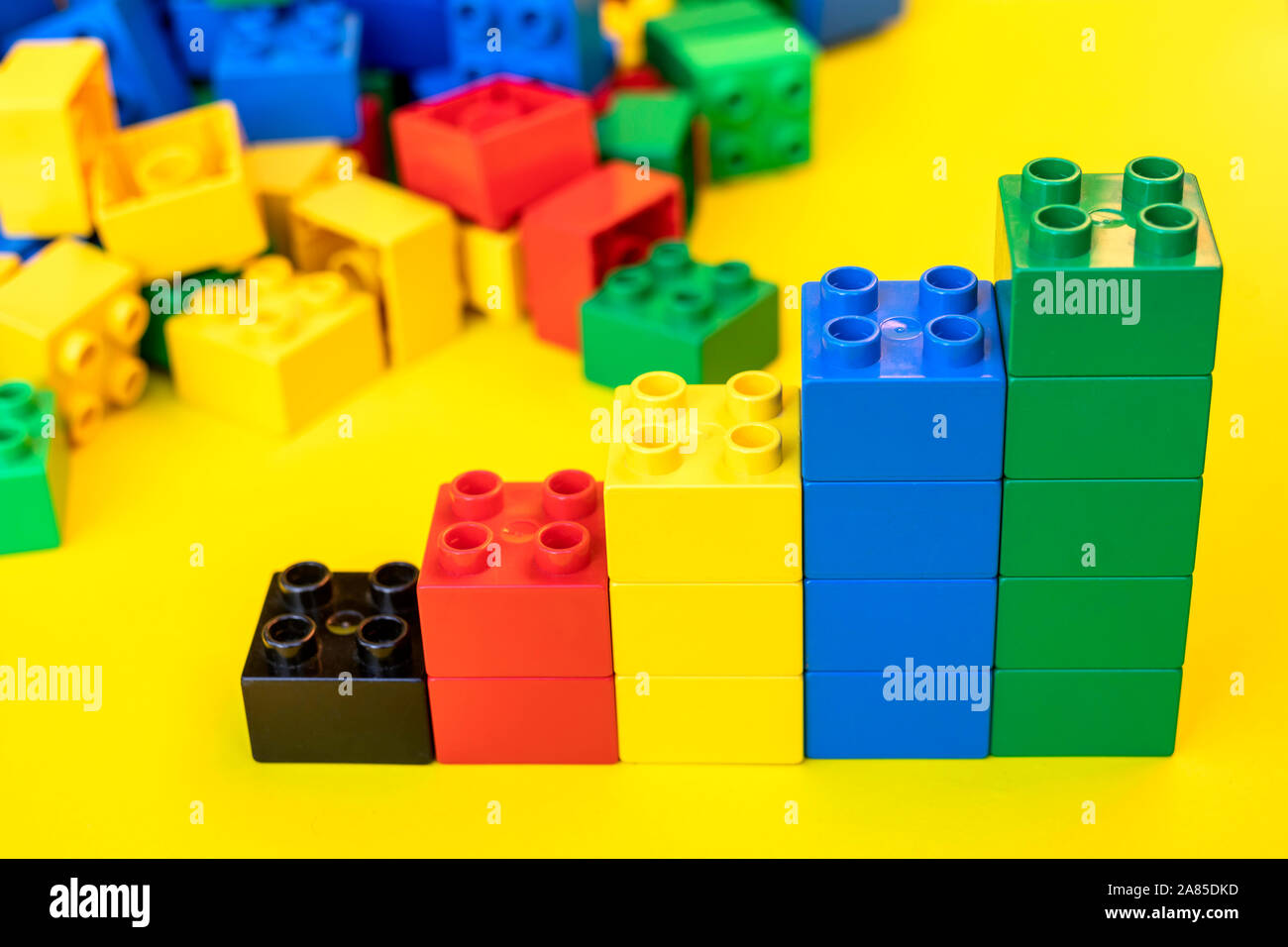 Blocs de construction en plastique Bar graphes toy briques sur fond jaune. Banque D'Images