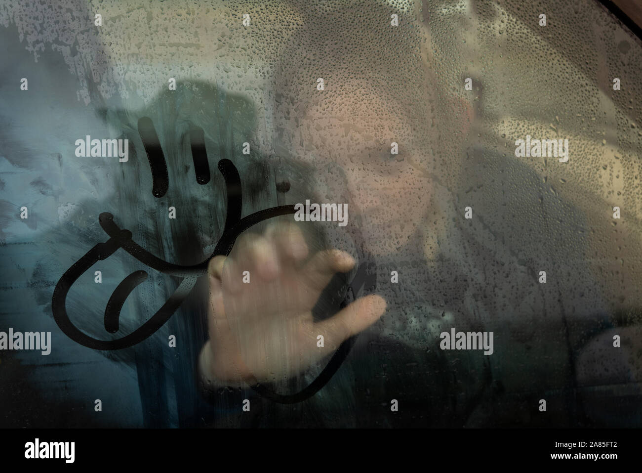 Jeune personne s'appuyant sur l'intérieur de la fenêtre de voiture brouillard Banque D'Images