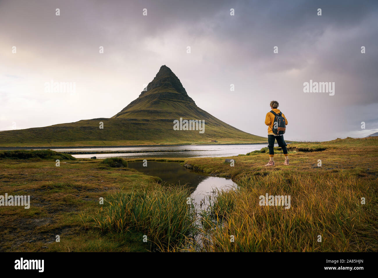 Jeune randonneur avec un sac à dos regarde le Kirkjufell mountain en Islande Banque D'Images