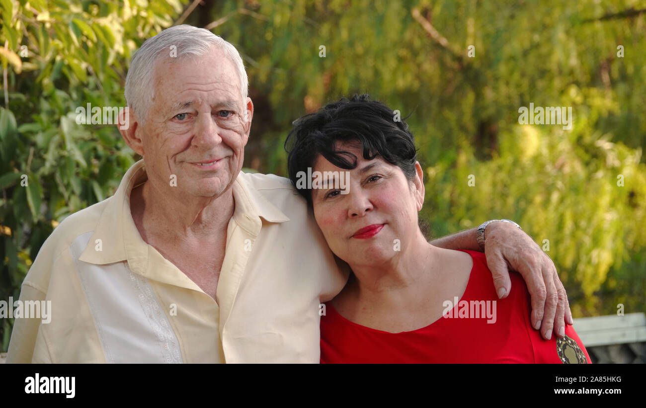 Heureux, vieux couple souriant. L'homme (80 ans) a son bras autour de l'épaule de sa femme (62 ans) d'origine hispanique. Banque D'Images