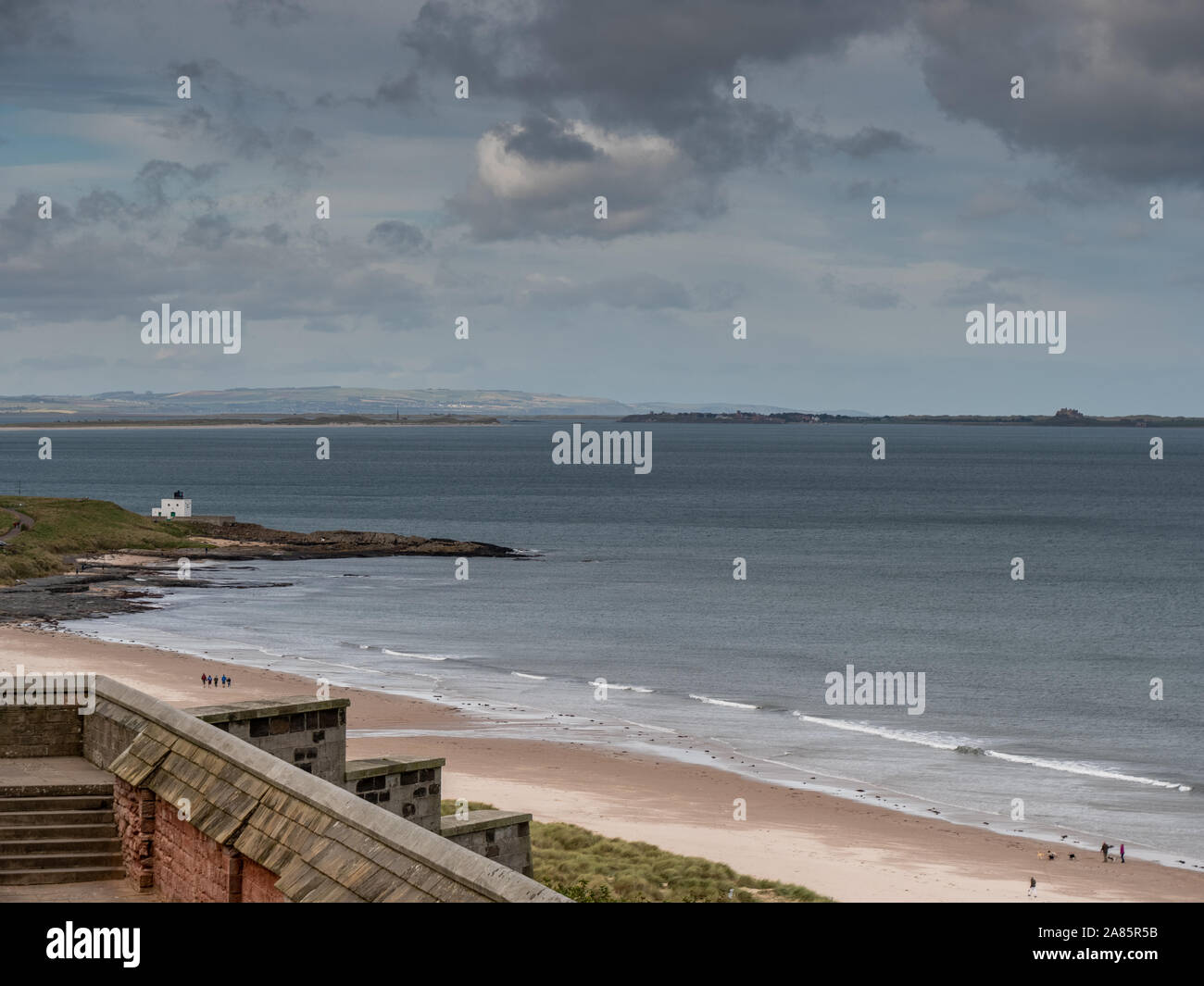 Voir l'île de Lindisfarne (saints) à travers la plage et la mer du château de Bamburgh, Northumberland, Angleterre. Banque D'Images