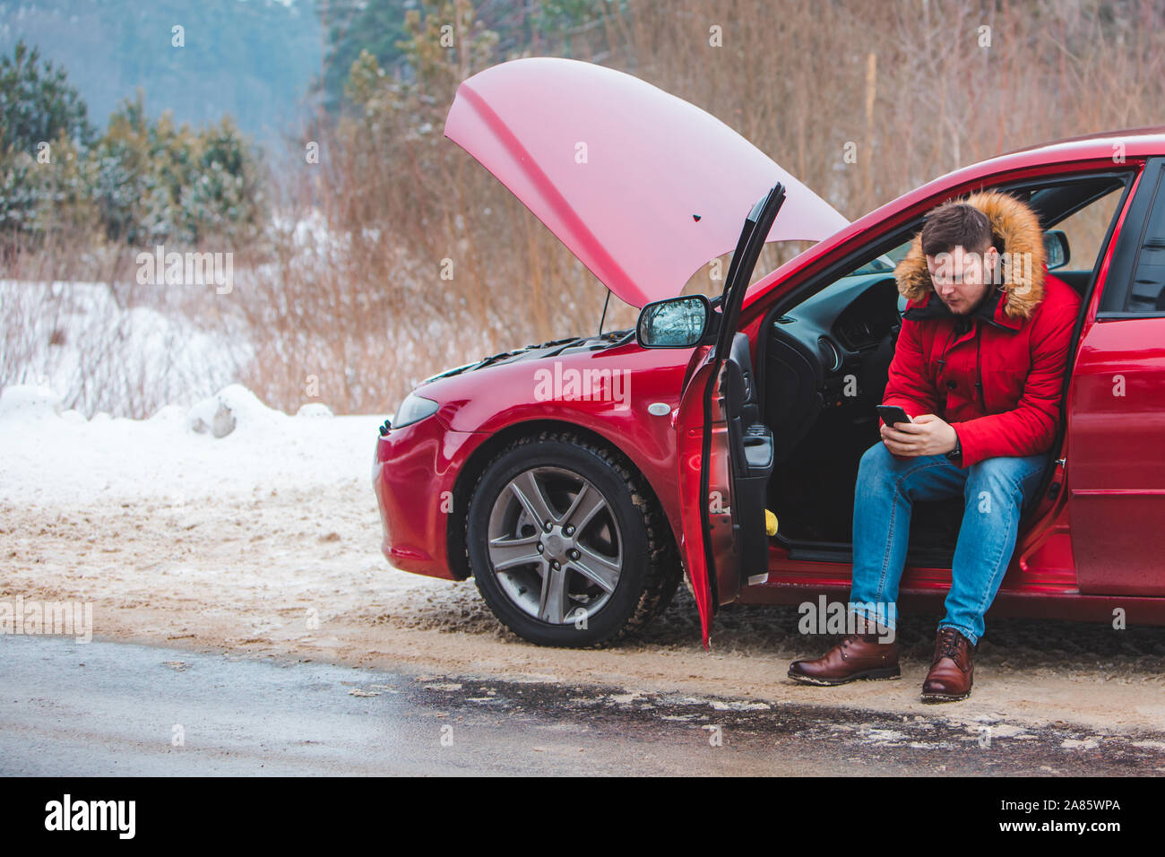 Man sitting in car appelant à l'aide. briser au winter speedway Banque D'Images