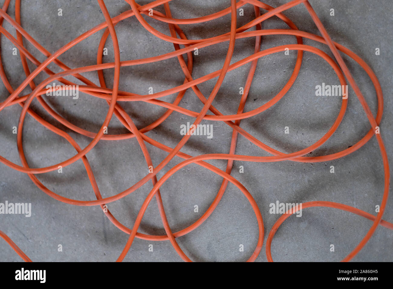 Un long câble électrique enchevêtrées sur un sol en béton gris Banque D'Images